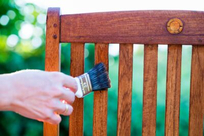 a person refinishing a chair, showing how to clean wood furniture to make them look new